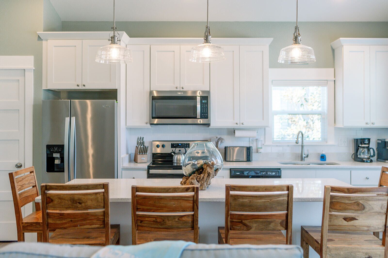Una cocina moderna con armarios blancos, electrodomésticos de acero inoxidable y sillas de madera.