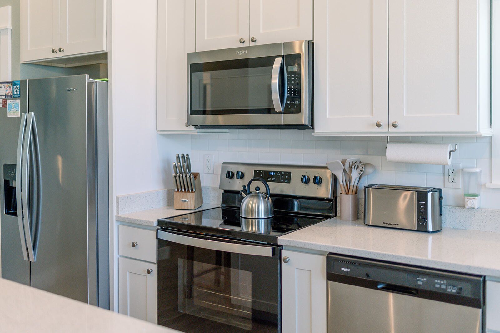 A modern kitchen with stainless steel appliances including a refrigerator, microwave, stove, and dishwasher.