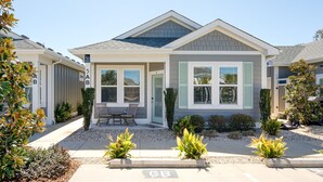 Ein modernes, zweistöckiges Haus mit Veranda, Garage und einem gepflegten Garten.