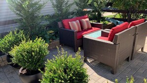 Un espace extérieur aménagé en terrasse, avec des meubles en osier, des plantes en pot et une petite table.