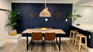 Un espace repas comprenant une table, des chaises, un luminaire suspendu et des œuvres d’art murales.