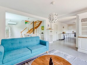 A modern living room with a blue sofa, a wooden coffee table, and a chandelier. - Les Nanous by Interhome (Saint-Raphaël)