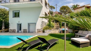 Ein zweistöckiges Haus mit Swimmingpool, Gartenmöbeln und einer Treppe, die zu einer zweiten Etage führt.