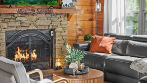 Ein gemütliches Wohnzimmer mit Kamin aus Stein, einer Ledersofa und einem runden Couchtisch.