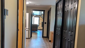 Un couloir doté d’un plancher en bois, de portes noires et d’où l’on aperçoit une pièce avec un ventilateur de plafond.