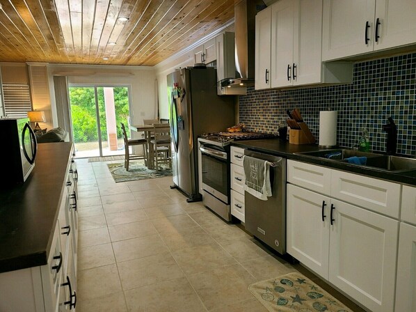 A modern kitchen with white cabinets, a black countertop, and a tiled backsplash.