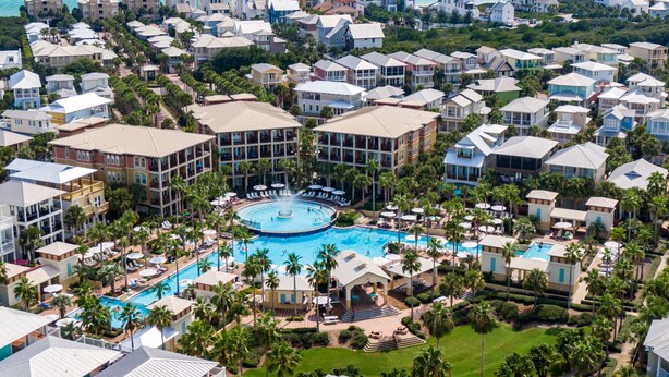 Un resort con varias edificaciones, una piscina central y vista al océano.