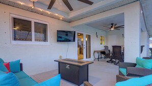 Ein möblierter Patio mit Korbmöbeln, einem Tisch und einem Deckenventilator.