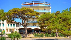 Un hotel de varios pisos con un atrium central, zona de estar al aire libre y un árbol destacado en primer plano.