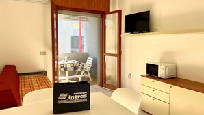Hotellihuone, jossa on ruokapöytä, tuolit, televisio, mikroaaltouuni ja minibaari.