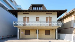 A two-story building with a balcony, a sign above the entrance, and a clear sky. - Holiday apartment with air conditioning (Lignano)