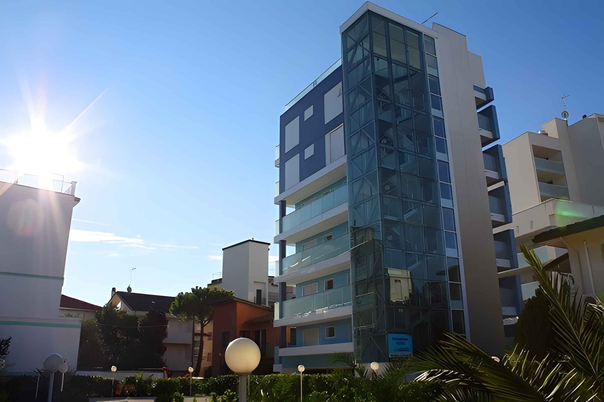 A multi-story building with a modern glass facade, surrounded by other buildings and greenery.