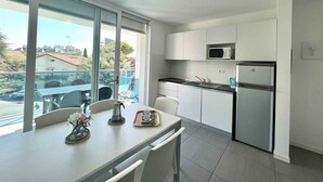 A modern kitchen with white cabinets, a stainless steel refrigerator, and a microwave. - Holiday apartment with balcony, air conditioning and internet (Lignano)