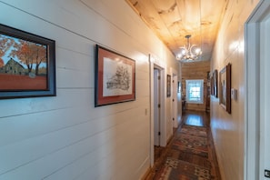 A hallway with wooden walls, framed pictures, and a patterned rug. - Georgia Bell's| Vintage Farmhouse by Chattahoochee (Helen)