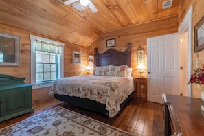 A wooden-paneled bedroom with a bed, nightstands, a dresser, and a door. - Georgia Bell's| Vintage Farmhouse by Chattahoochee (Helen)