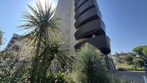 A modern building with a curved facade and multiple balconies. - Holiday apartment with balcony and air conditioning (Lignano)