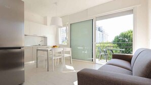 A modern kitchen with white cabinets, a stainless steel refrigerator, and a dining area with a table and chairs. - Holiday apartment mit Klimaanlage und Balkon (Lignano)