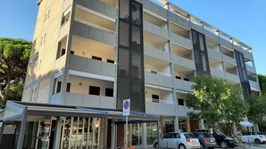 Un immeuble à plusieurs étages doté d’une architecture moderne, avec des balcons et de grandes fenêtres.