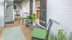 A covered outdoor area with a staircase, two chairs, a bench, and potted plants. - The Hideaway Suite: Sauna & Lux Amenities (Staunton)