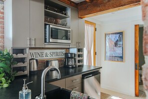 A kitchen with a coffee maker, a microwave, and a sign that reads "WINE & SPIRITS".