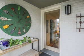 A room with a green clock, a wooden bench, and a door leading to another room.