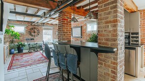 A modern kitchen with exposed brick walls, a bar area, and a dining space with a red rug.