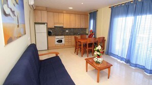 A compact living space with a kitchenette, a dining area, and a sofa. - Holiday apartment with pool (Roses)