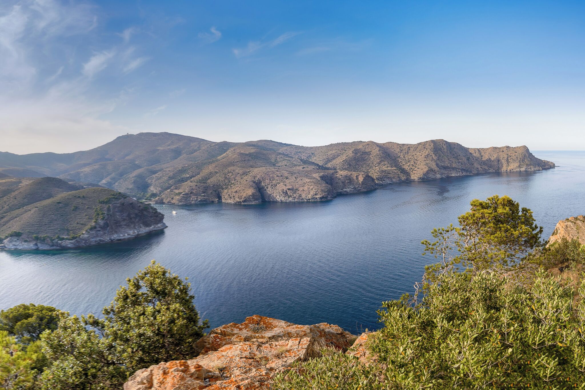 A coastal landscape with mountains and a calm sea.