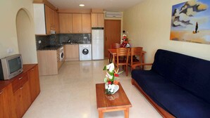 A compact living space with a kitchenette, a dining area, and a sofa. - Holiday apartment with pool (Roses)