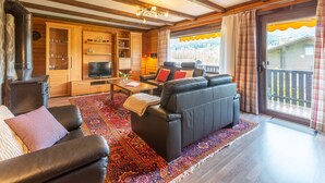 Un salon chaleureux avec une cheminée, des meubles en bois et une grande fenêtre agrémentée de rideaux.