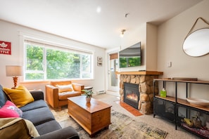 Una sala de estar con chimenea, un sofá, una mesa de centro y un televisor.