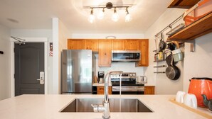 A modern kitchen with stainless steel appliances, wooden cabinets, and a marble countertop.