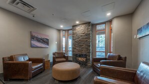 A modern lounge area with leather sofas, a stone accent wall, and artwork on the walls.