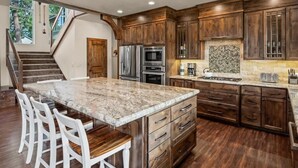 A kitchen with a large island, wooden cabinets, stainless steel appliances, and a herringbone tile backsplash. - Luxury Family Waterfront Home | Dock + SUP/Kayak (Sagle)