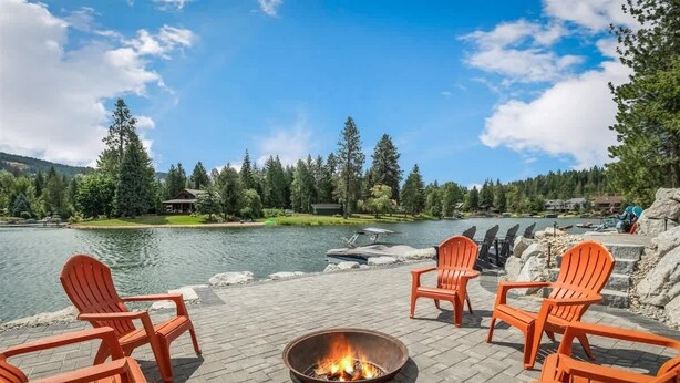 A lakeside deck with outdoor seating and a fire pit. - Luxury Family Waterfront Home | Dock + SUP/Kayak (Sagle)