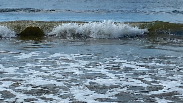 Ein Strand mit brechenden Wellen.