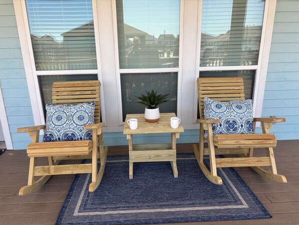 Two wooden rocking chairs with patterned cushions, a small table with a potted plant, and a blue rug on a wooden deck. - Everything Beachy! Beautiful home Close to the Beach (Bolivar Peninsula)