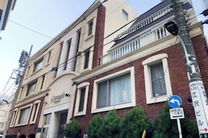 A multi-story building with a classic architectural style, featuring a prominent entrance with a sign, large windows, and a balcony on the upper floor. - Granado Roppongi (Minato-ku)