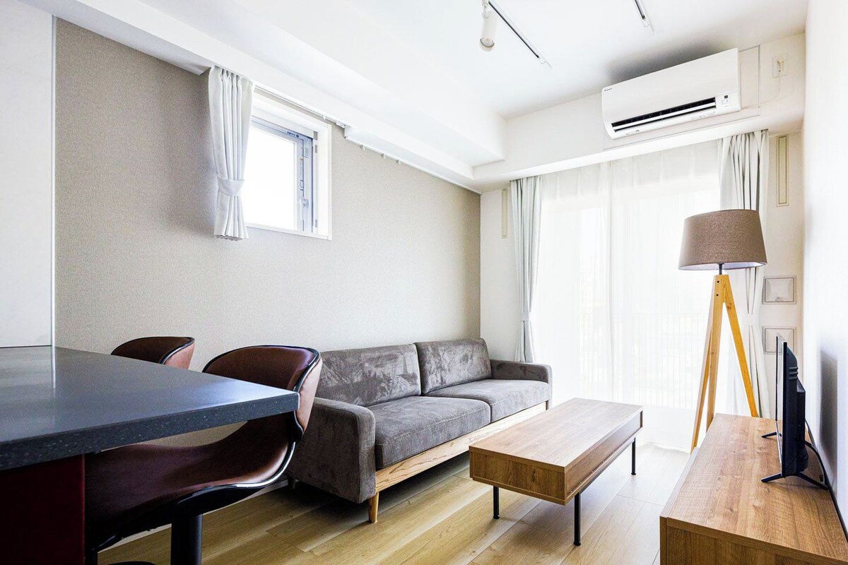 A modern living room with a sofa, a coffee table, a dining table, and a lamp.