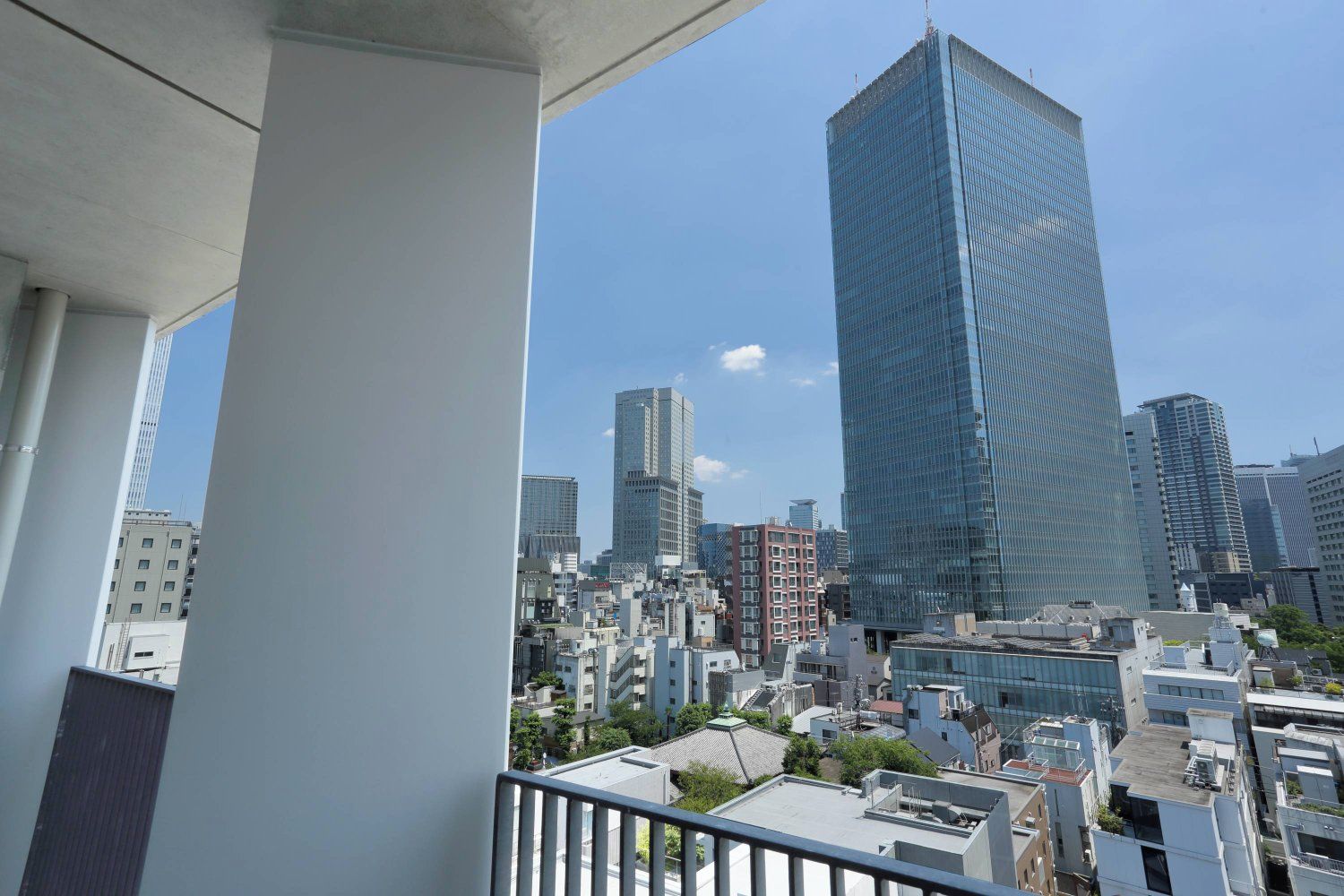 A high-rise building with a glass facade, surrounded by other buildings and a clear sky.