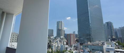 A high-rise building with a glass facade, surrounded by other buildings and a clear sky.