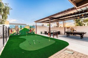 Un jardin avec une pelouse artificielle, une table de billard et une fresque murale.