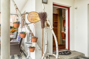 L’entrée d’un hôtel, avec une porte en bois, une enseigne portant un texte écrit à la main et des plantes en pot.