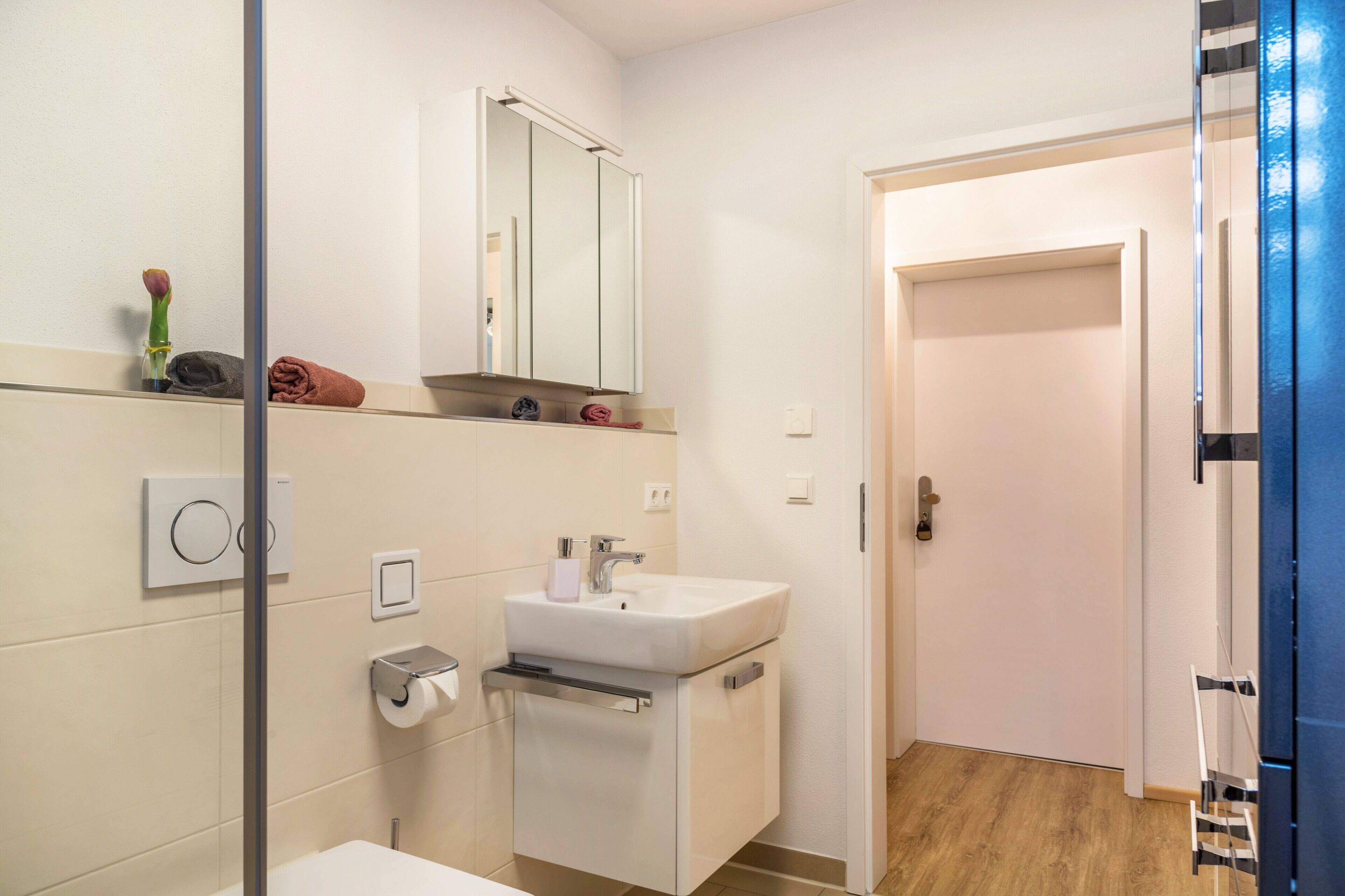 Une salle de bain moderne avec un lavabo blanc, un miroir et un porte-serviettes.