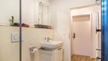 Une salle de bain moderne avec un lavabo blanc, un miroir et un porte-serviettes.