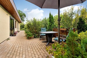 Un patio con una mesa y sillas, una cerca de madera y una variedad de plantas.