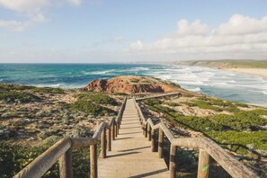 A wooden boardwalk leading to a rocky coastline with ocean views.