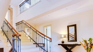 A spacious foyer with a grand staircase, a console table with a mirror, and a patterned rug. - 5 Star Villa Hibiscus - Quinta Verde Retreat (Algarve)