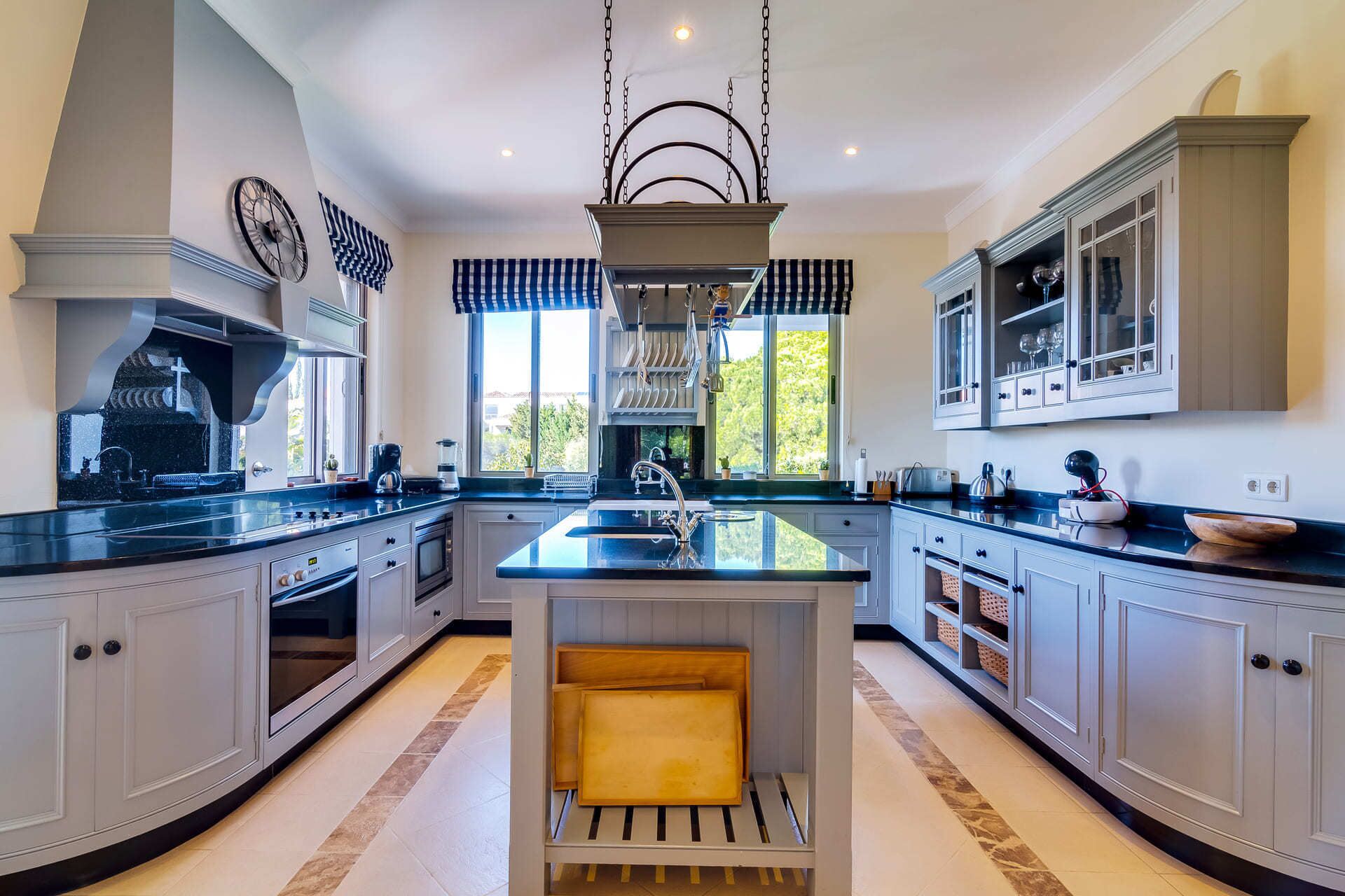 A spacious kitchen with a central island, large windows, and modern cabinetry.