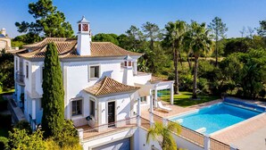 A white villa with a swimming pool, surrounded by lush greenery and palm trees. - 5 Star Villa Hibiscus - Quinta Verde Retreat (Algarve)